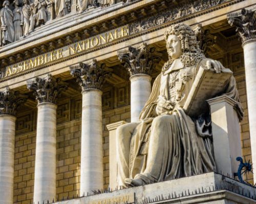 Low angle view of the statue of Francois d'Aguesseau in front of the neoclassical facade of the Palais Bourbon, seat of the french National Assembly in Paris, France.